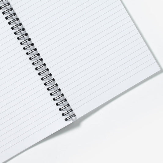 A spiral notebook open flat showing ruled lined pages and the black spiral wire.