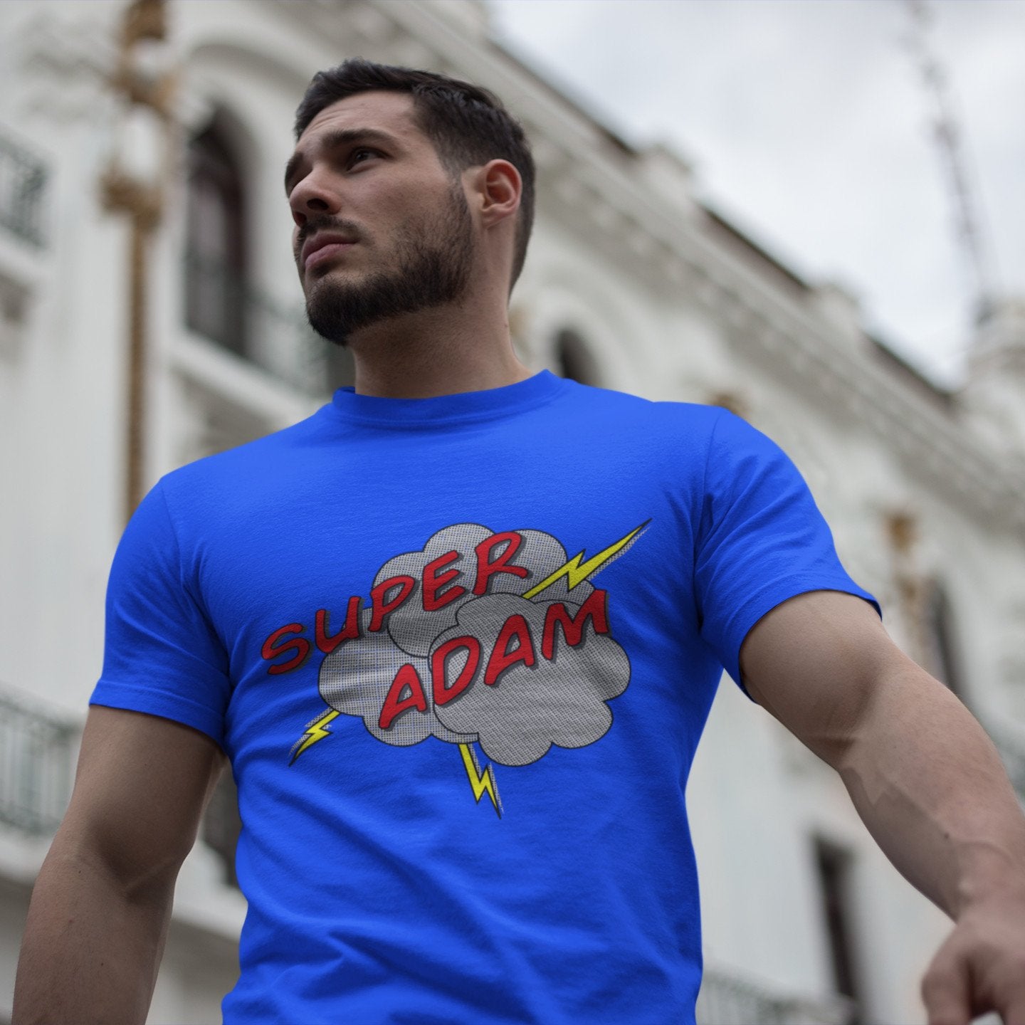 Man wearing personalised superhero style half toned comic speech balloon design on a royal blue cotton crewneck t-shirt