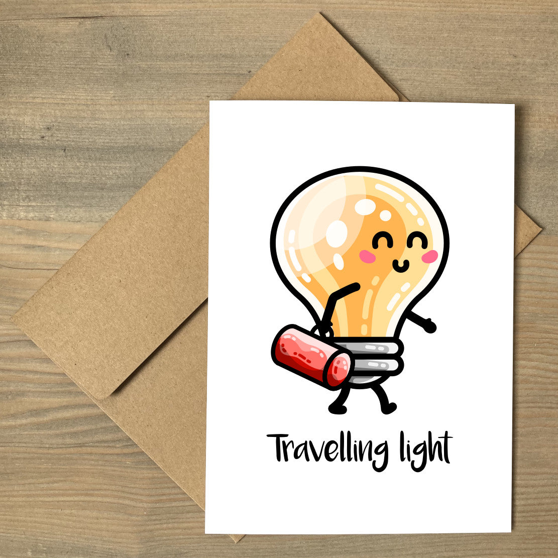 A white greeting card lying flat on a brown envelope, with a design of a kawaii cute lightbulb walking and carrying a bag with words above saying 'travelling light'