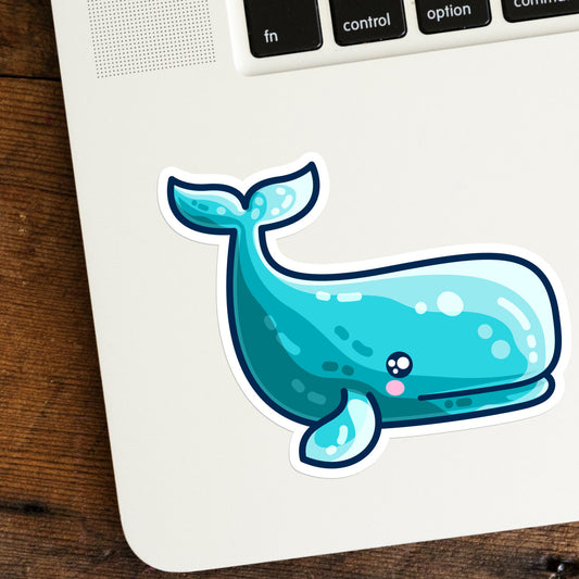 a cute turquoise sperm whale shaped vinyl sticker shown stuck on the bottom left hand corner of a laptop computer keyboard